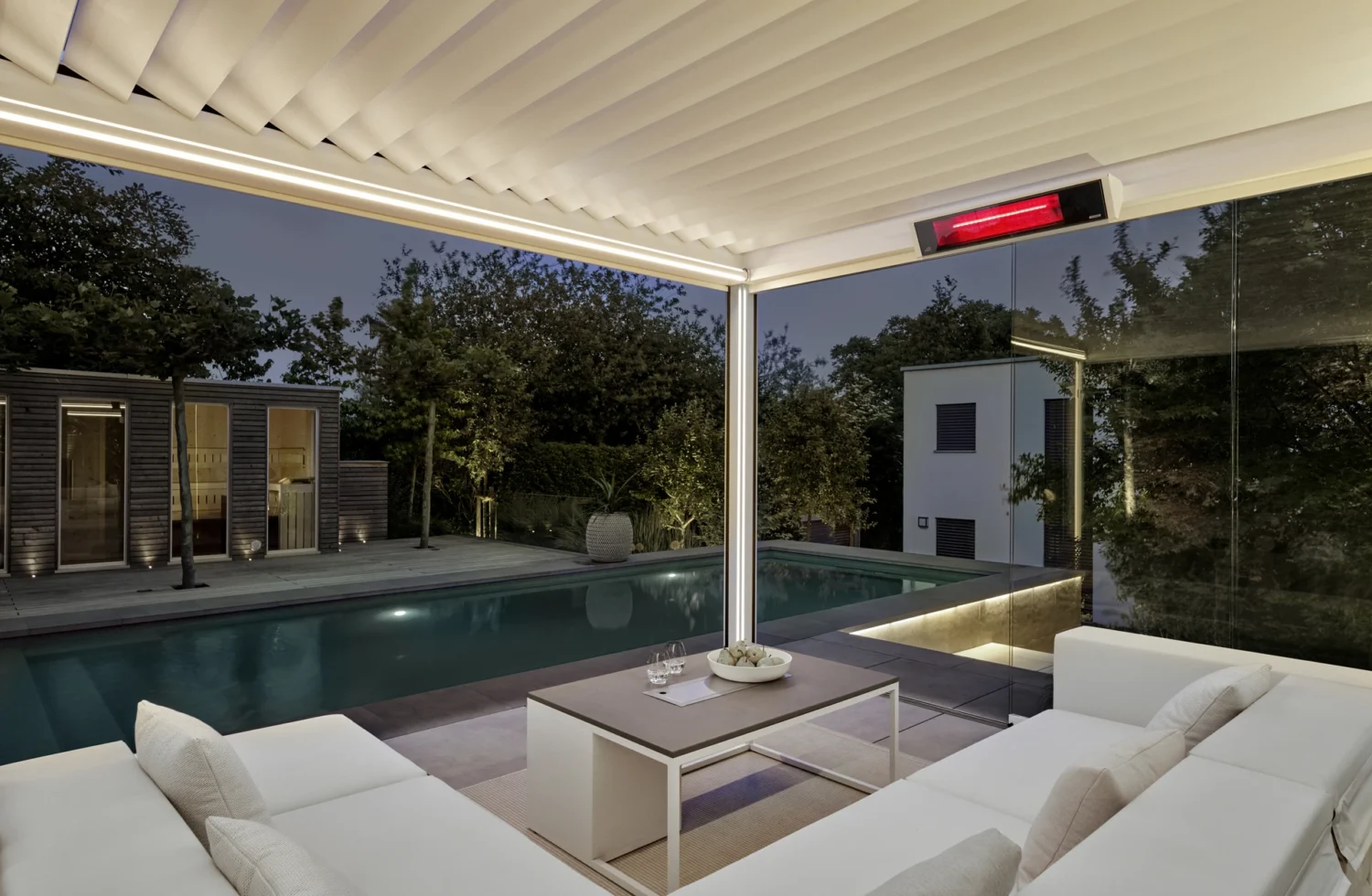Moderne Outdoor-Lounge mit Pool und stilvoller Beleuchtung bei Nacht