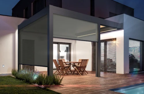 Moderne überdachte Terrasse mit Holzmöbeln und Beleuchtung am Abend